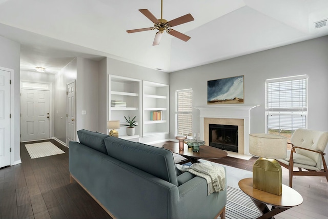 living room with ceiling fan, vaulted ceiling, built in features, and dark wood-type flooring