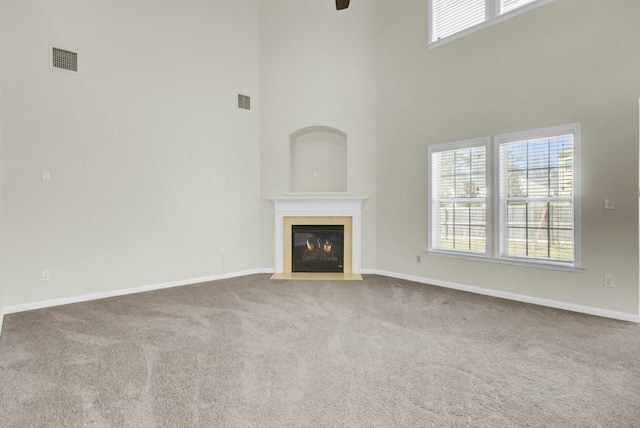 unfurnished living room featuring a fireplace with flush hearth, baseboards, visible vents, and carpet flooring