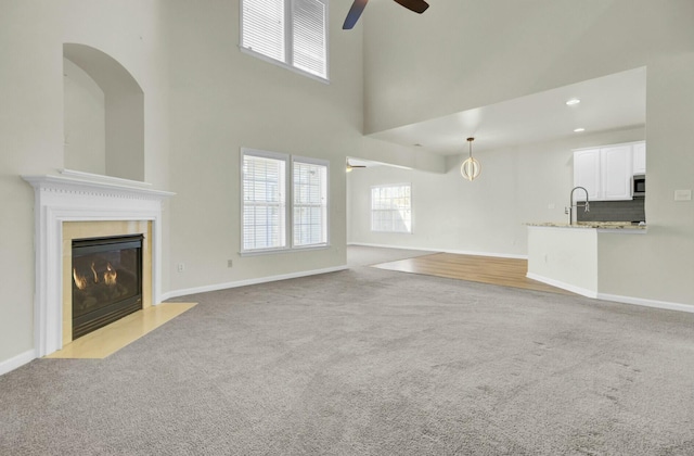 unfurnished living room with recessed lighting, light carpet, a fireplace, a ceiling fan, and baseboards