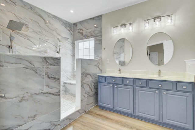 full bathroom featuring a sink, double vanity, wood finished floors, and a marble finish shower