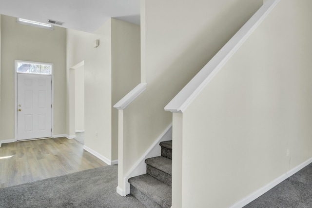 entrance foyer featuring light carpet, stairway, visible vents, and baseboards