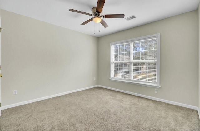 empty room featuring carpet floors, visible vents, baseboards, and a ceiling fan