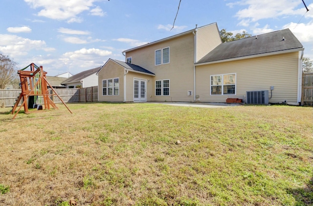 rear view of property featuring french doors, a playground, a lawn, cooling unit, and a fenced backyard