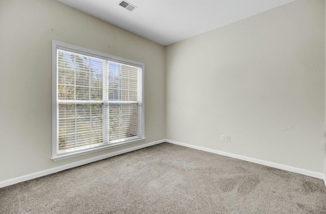 carpeted spare room with a healthy amount of sunlight, visible vents, and baseboards