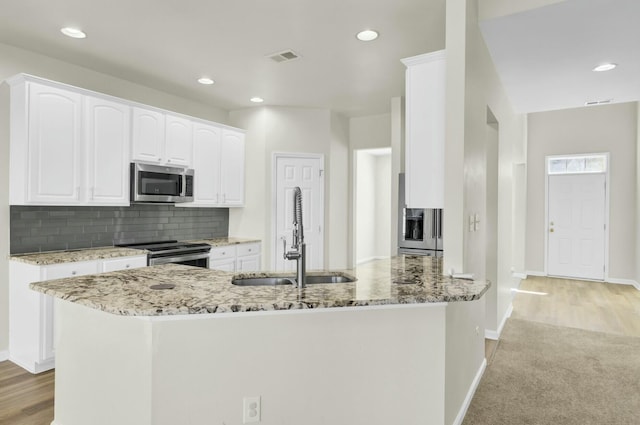 kitchen featuring a sink, light stone countertops, stainless steel appliances, white cabinetry, and backsplash