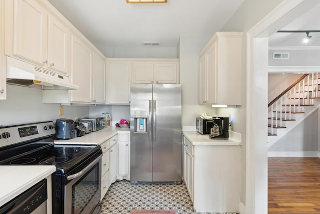 kitchen with appliances with stainless steel finishes, rail lighting, and white cabinets