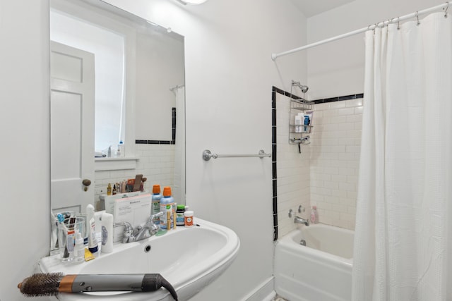 bathroom with shower / tub combo with curtain, sink, and tile walls