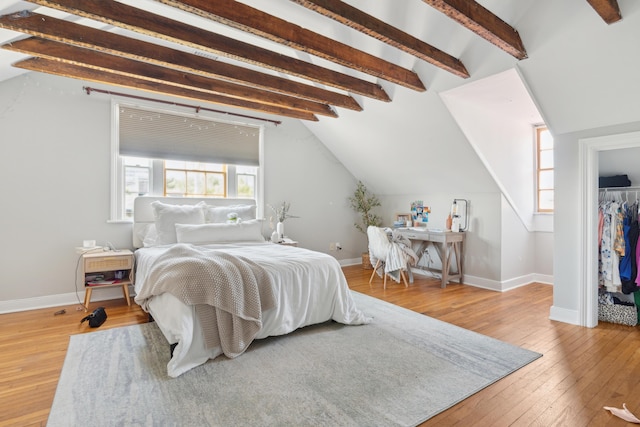 bedroom with multiple windows, hardwood / wood-style floors, lofted ceiling with beams, and a closet