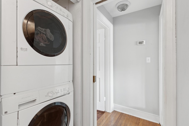 washroom with light hardwood / wood-style flooring and stacked washer and clothes dryer