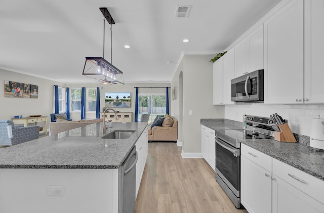 kitchen with appliances with stainless steel finishes, decorative light fixtures, a kitchen island with sink, and white cabinetry