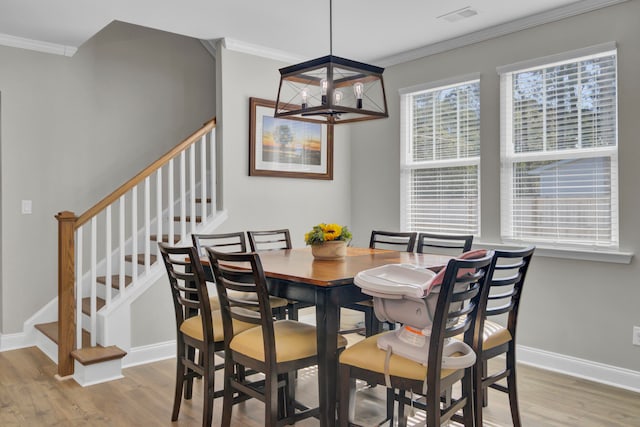 dining area featuring crown molding, a notable chandelier, and light hardwood / wood-style floors