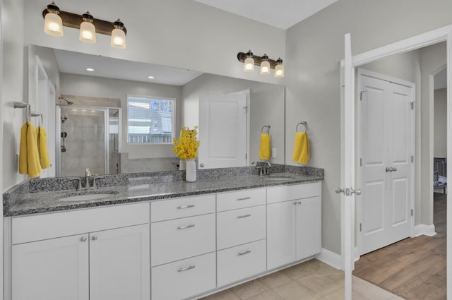 bathroom with a shower with door, hardwood / wood-style floors, and vanity