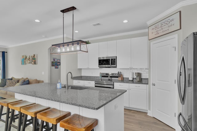 kitchen featuring sink, a breakfast bar, decorative light fixtures, white cabinetry, and appliances with stainless steel finishes