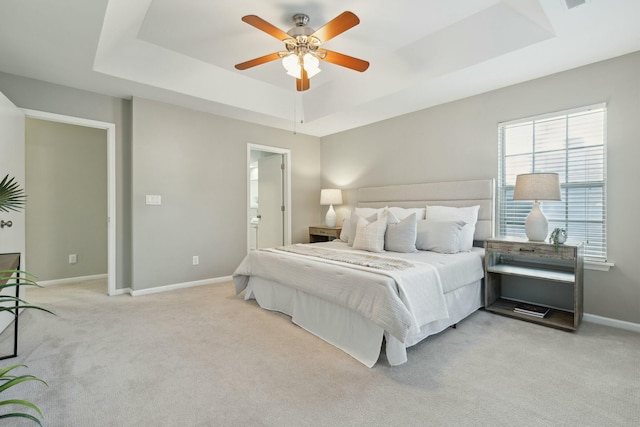 bedroom with light carpet, ceiling fan, a raised ceiling, and baseboards