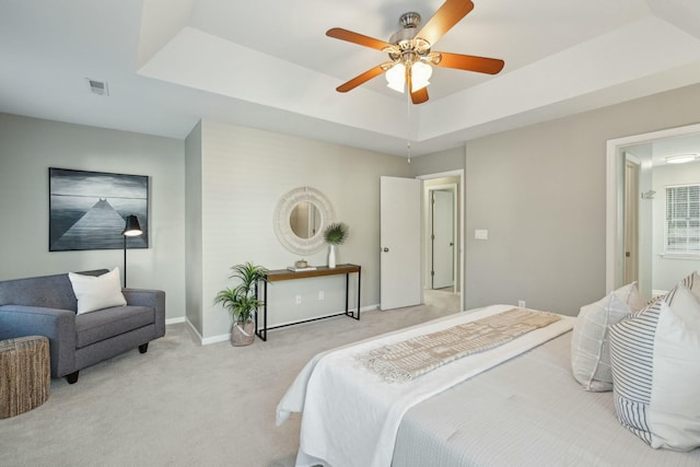 bedroom with baseboards, visible vents, a raised ceiling, a ceiling fan, and light colored carpet