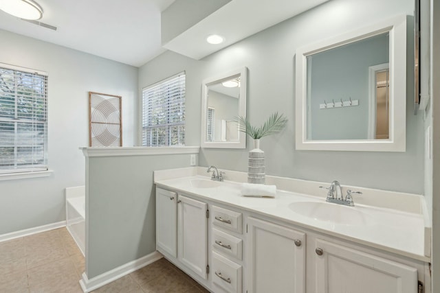 full bath featuring double vanity, a sink, a bath, and tile patterned floors