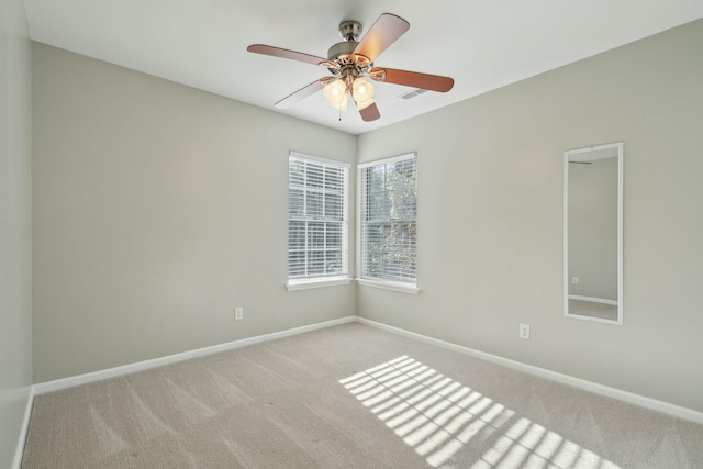 empty room with a ceiling fan, light carpet, and baseboards