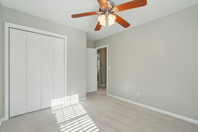 unfurnished bedroom with a ceiling fan, baseboards, a closet, and light colored carpet