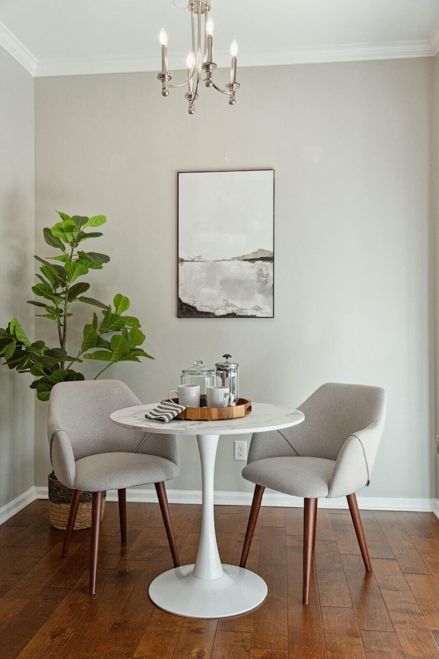 dining room featuring dark wood finished floors, breakfast area, ornamental molding, a chandelier, and baseboards