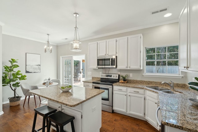 kitchen featuring white cabinetry, stainless steel appliances, a sink, and a center island