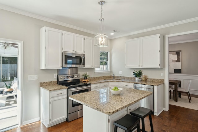 kitchen with light stone counters, decorative light fixtures, stainless steel appliances, white cabinetry, and a kitchen island