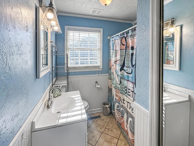 bathroom featuring toilet, a textured ceiling, ornamental molding, vanity, and tile patterned flooring