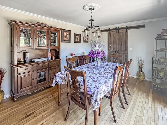 dining area featuring ornamental molding, a barn door, and light wood-type flooring