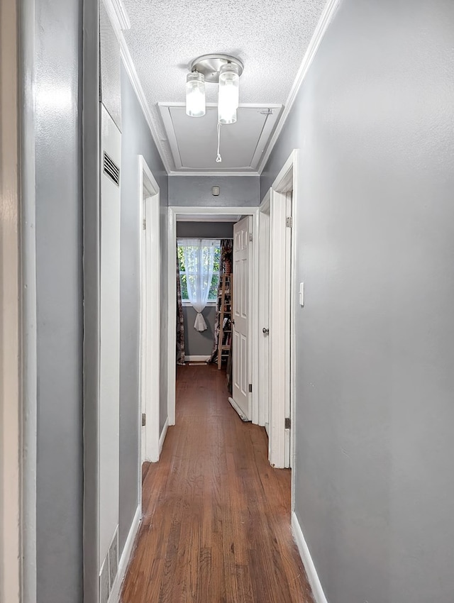 corridor with a textured ceiling, dark hardwood / wood-style floors, and ornamental molding