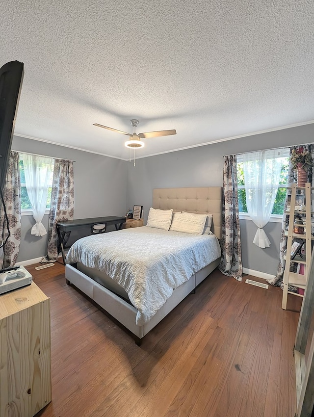 bedroom featuring hardwood / wood-style floors, ceiling fan, a textured ceiling, and multiple windows