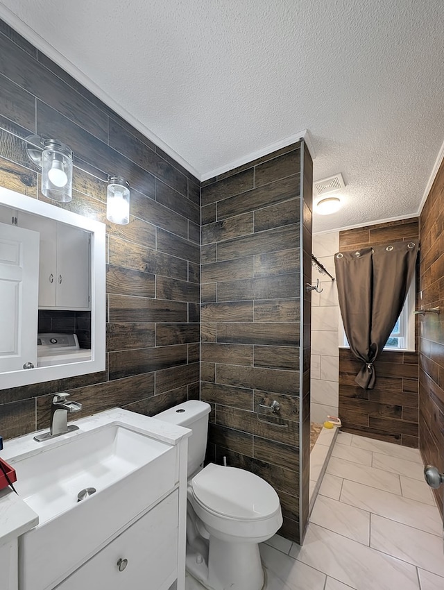 bathroom featuring vanity, toilet, a textured ceiling, and wooden walls