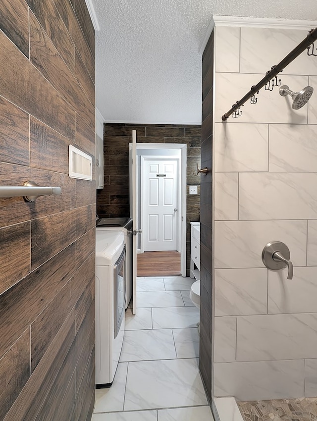 bathroom with washer and dryer, a shower, and a textured ceiling