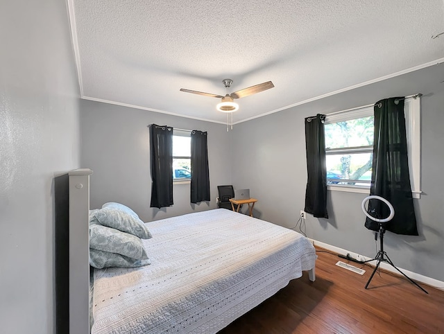 bedroom featuring hardwood / wood-style floors, ceiling fan, a textured ceiling, and multiple windows