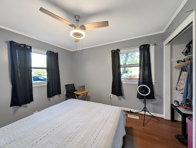 bedroom featuring multiple windows, ceiling fan, crown molding, and dark wood-type flooring