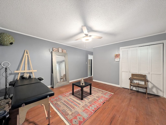 living area featuring wood-type flooring, a textured ceiling, ceiling fan, and crown molding