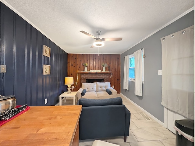 bedroom with wood walls, a brick fireplace, ceiling fan, ornamental molding, and a textured ceiling