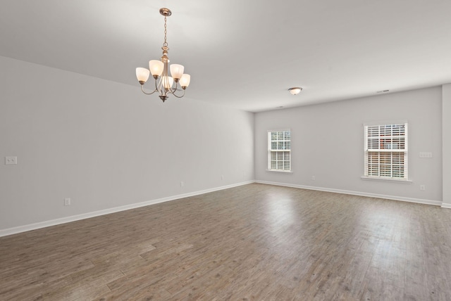 empty room with a chandelier and wood-type flooring