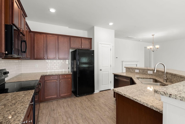 kitchen with light stone countertops, black appliances, sink, pendant lighting, and light hardwood / wood-style flooring