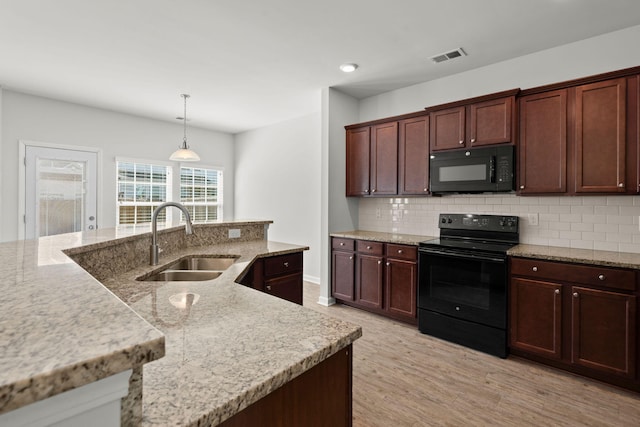 kitchen featuring sink, black appliances, pendant lighting, light wood-type flooring, and tasteful backsplash