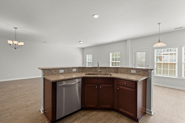 kitchen featuring a kitchen island with sink, sink, stainless steel dishwasher, and hardwood / wood-style floors