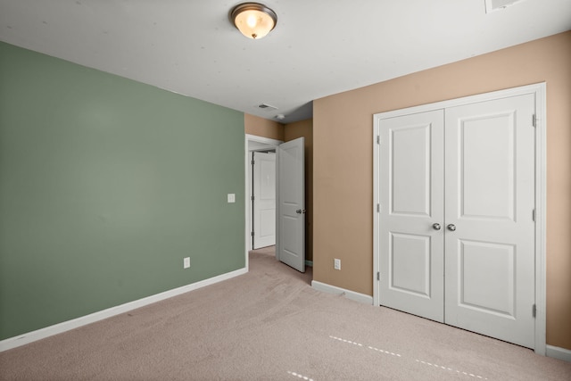 unfurnished bedroom featuring light colored carpet and a closet