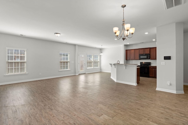 unfurnished living room featuring a notable chandelier and wood-type flooring