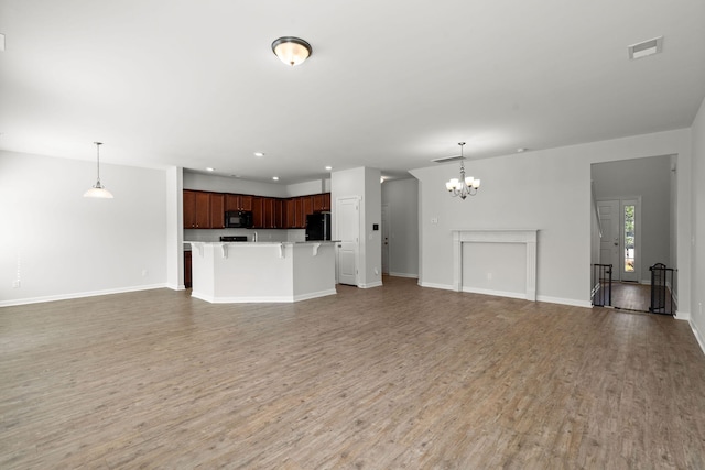 unfurnished living room featuring a notable chandelier and hardwood / wood-style flooring