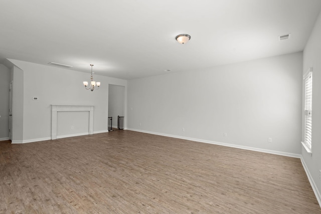 unfurnished living room featuring a notable chandelier and wood-type flooring