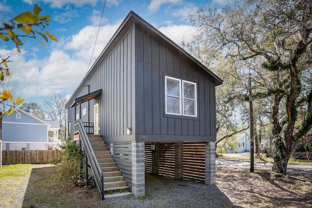 exterior space featuring board and batten siding, stairs, and fence