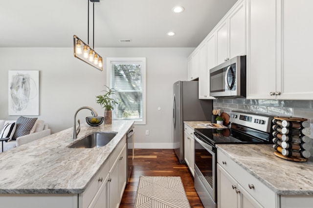 kitchen with visible vents, an island with sink, a sink, backsplash, and appliances with stainless steel finishes