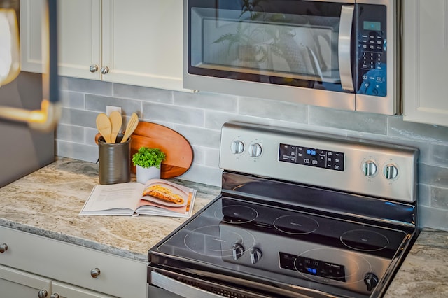 room details with decorative backsplash, light stone countertops, white cabinetry, and appliances with stainless steel finishes