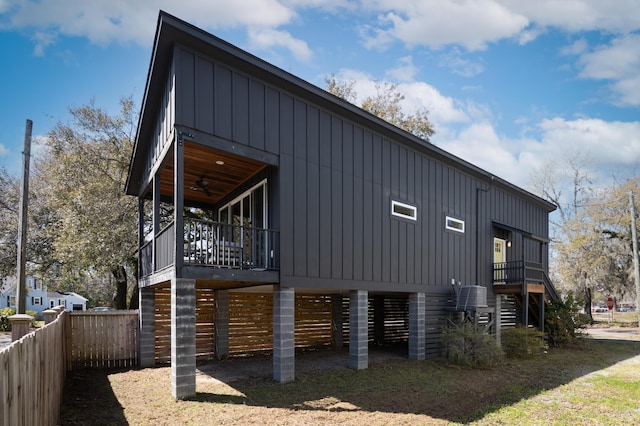 view of side of home featuring stairs, fence, a ceiling fan, and board and batten siding