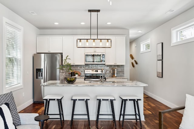 kitchen featuring a sink, decorative backsplash, appliances with stainless steel finishes, and a breakfast bar area