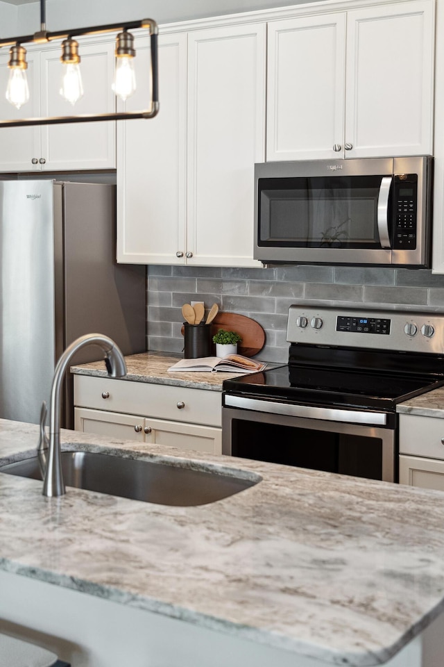 kitchen featuring backsplash, white cabinetry, stainless steel appliances, and a sink