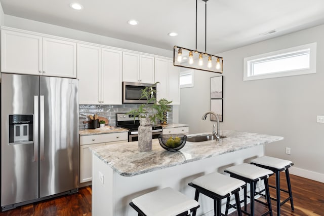 kitchen with visible vents, an island with sink, a sink, tasteful backsplash, and stainless steel appliances